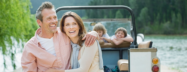 family smiling in front of a lake